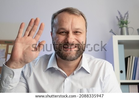 Middle aged man gestures hello at the camera. Make online calls and live video conference chat using a computer. Home office close up webcam view, Online VideoChat concept Stock photo © 