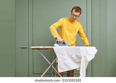 Middle aged man in glasses ironing his shirt - Powered by Shutterstock