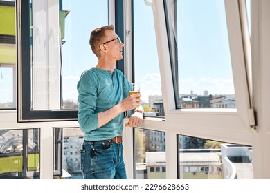 Middle aged man in glasses stands on balcony of high-rise building - Powered by Shutterstock