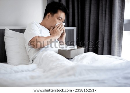 Middle aged man have a stuffy nose,runny nose,blow or wipe one's nose with tissue paper,asian male have a fever and cold or flu,respiratory disease,respiratory tract infection,resting in bed at home