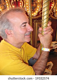 A Middle Aged Man Having A Great Time While Riding On The Merry Go Round.