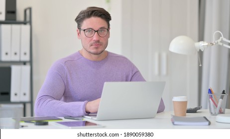 Middle Aged Man With Laptop Looking At The Camera 