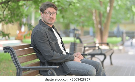 Middle Aged Man Looking at Camera while Sitting Outdoor