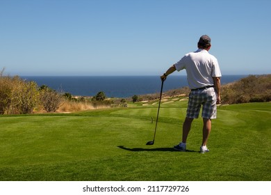 Middle Aged Man Looking Out Over Ocean Side Tropical Golf Course View While Waiting To Tee Off. Copy Space.