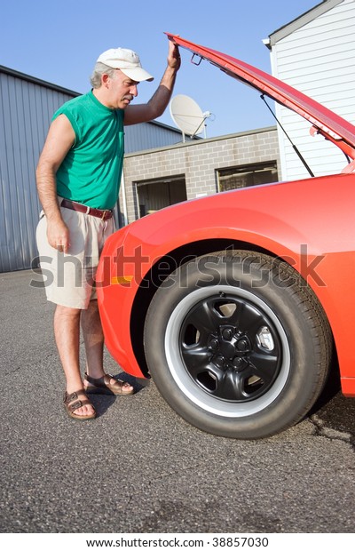 A middle
aged man looking under the hood of a
car.