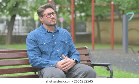 Middle Aged Man Pondering while Sitting Outdoor