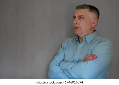 Middle Aged Man Portrait With Crossed Hand. 40 Years Man Not Looking At Camera. Blue Business Shirt Is Dressed. Thinking Face And Calm Emotions