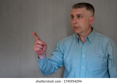 Middle Aged Man Portrait With Pointing Hand. 40 Years Man Not Looking At Camera. Blue Business Shirt Is Dressed. Thinking Face And Calm Emotions