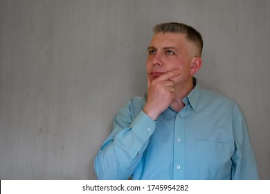 Middle Aged Man Portrait Touching Her Face With Hand. 40 Years Man Not Looking At Camera. Blue Business Shirt Is Dressed. Thinking Face And Calm Emotions