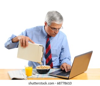 Middle Aged Man Pouring His Breakfast Cereal Into Bowl. He Is Is Busy Working On His Laptop Computer And Not Paying Attention To What He Is Doing. Horizontal Format Isolated Over White.