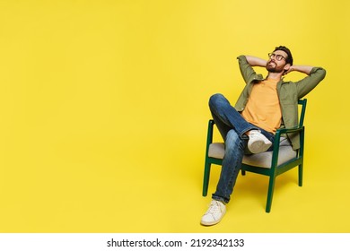 Middle aged man relaxing with eyes closed holding hands behind head, sitting in armchair over yellow background, free copy space. Relaxation and comfort concept - Powered by Shutterstock