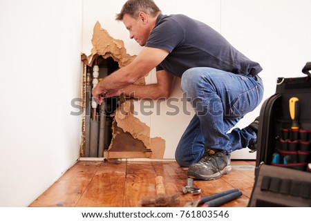 Middle aged man repairing burst water pipe