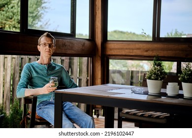 Middle aged man is resting on the veranda with a glass of wine - Powered by Shutterstock