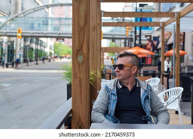 Middle Aged Man Sitting At Outdoor Restaurant Patio With Copy Space