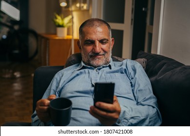 Middle Aged Man Sitting Sofa Using Mobile Phone At Home