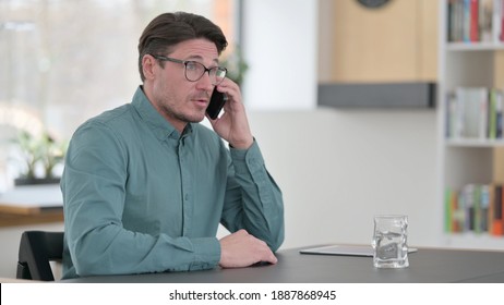 Middle Aged Man Talking On Phone At Work 