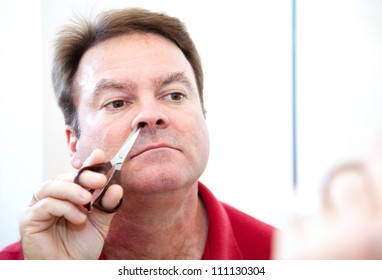 Middle Aged Man Trimming His Nose Hair With Grooming Scissors.