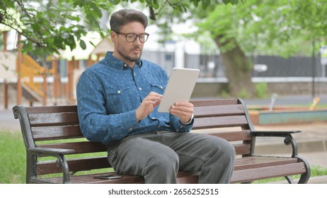 Middle Aged Man Using a Digital Tablet while Sitting Outdoor