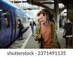 Middle aged man using his smartphone while waiting for the train at the train station
