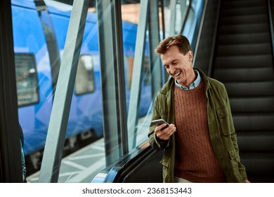 Middle aged man using his smartphone while on the escalator at the train station