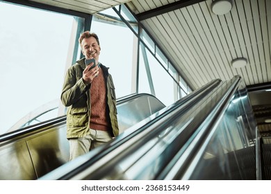 Middle aged man using his smartphone while on the escalator at the train station