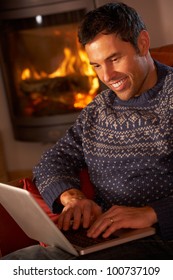 Middle Aged Man Using Laptop Computer By Cosy Log Fire - Shutterstock ID 100737109