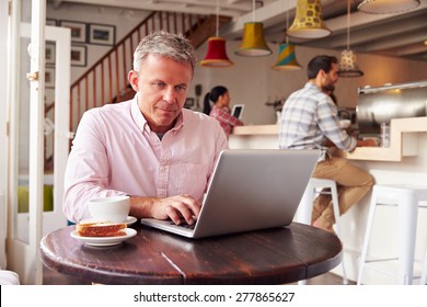 Middle Aged Man Using Laptop In A Cafe