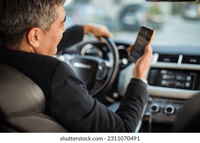 Middle aged man using a smart phone while driving a car - Powered by Shutterstock