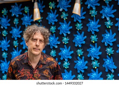 A middle aged man wearing an Asian themed shirt poses in front of a cool, unusual background of blue swirly flowers, while visiting Japan. - Powered by Shutterstock