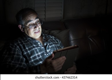 Middle aged man wearing pajamas reading tablet at night in bed looking scared or surprised with copy space - Powered by Shutterstock