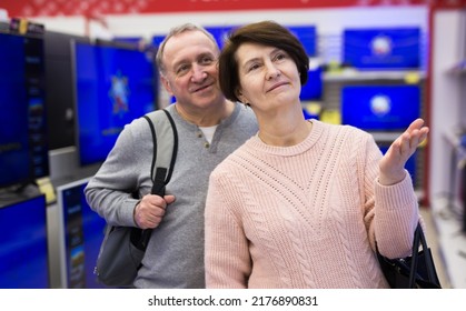 Middle Aged Man And Woman Choosing TV While Shopping In Electronic Store.