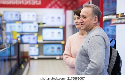 Middle Aged Man And Woman Choosing TV While Shopping In Electronic Store.