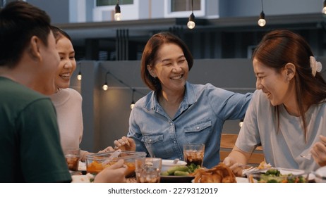 Middle aged mom smile joy look at young grown up kid child with love care good warm time. Asia people woman adult older mum parent sitting at home night dinner outdoor house party happy life moment. - Powered by Shutterstock