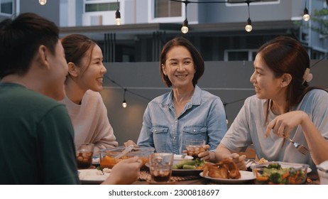 Middle aged mom smile joy look at young grown up kid child with love care good warm time. Asia people woman adult older mum parent sitting at home night dinner outdoor house party happy life moment. - Powered by Shutterstock