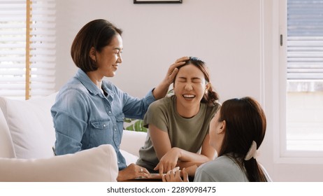 Middle aged mom smile look at two grown up kid child relax hug cuddle stroking with love care warm time. Asia people woman adult older mum parent sitting at home sofa sweet trust moment happy life. - Powered by Shutterstock