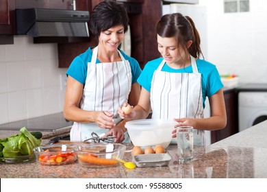middle aged mother teaching teen daughter baking in kitchen