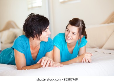 Middle Aged Mother And Teen Daughter Chatting On Bed