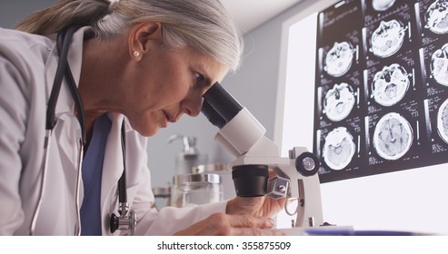 Middle aged neurologist female researching with microscope