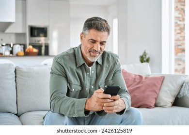 Middle aged old man using smartphone relaxing on couch at home. Happy senior mature male user holding cellphone browsing internet, texting messages on mobile cell phone technology sitting on sofa. - Powered by Shutterstock