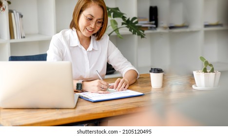 Middle Aged Older Asian Business Woman Watching Professional Training Class, Online Webinar On Laptop Computer Remote Working, Distance Learning In Office, Conference Calling In Virtual Chat Meeting.