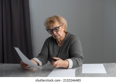 Middle Aged Older Woman Housewife Reading Paper Letter Or Bill Sitting In Kitchen At Home Office, Checking Financial Taxes Fees, Reviewing Bank Account Loan Rates Information, Medical Insurance Cost