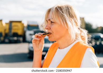 Middle Aged Portrait Of Worker Engineer Woman With Orange Vest Eating Cookies. Female Truck Driver 