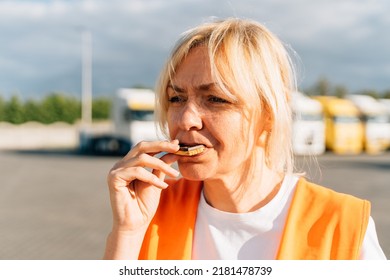 Middle Aged Portrait Of Worker Engineer Woman With Orange Vest Eating Cookies. Female Truck Driver 