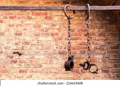 Middle aged prisoners chains and cuffs over a brick wall