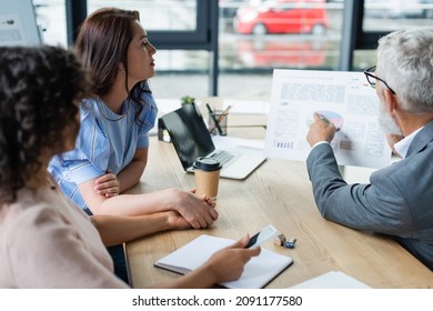 Middle Aged Sales Manager Showing Mortgage Graphs To Interracial Lesbian Couple In Real Estate Agency