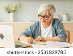 Middle aged senior woman using laptop computer writing notes at home. Focused mature old businesswoman work in home office making written records doing online work. Mature boss professional worker