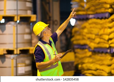 Middle Aged Shipping Company Worker Counting Pallets In Warehouse Before Dispatching