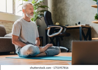 Middle Aged Sport Man Doing Yoga And Fitness At Home Using Laptop