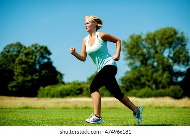 Middle Aged Sports Woman Running On Grass Field.