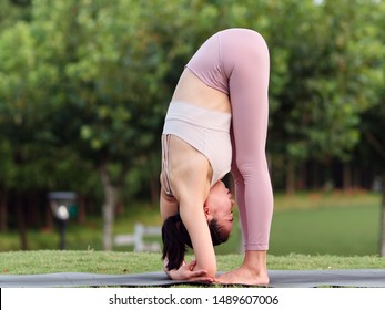 Middle Aged Sporty Attractive Woman Practicing Yoga Barefoot On The Mat In The Meadow With Forest Background, Working Out, Wearing Sportswear, Pants And Top, Outdoor Full Length.